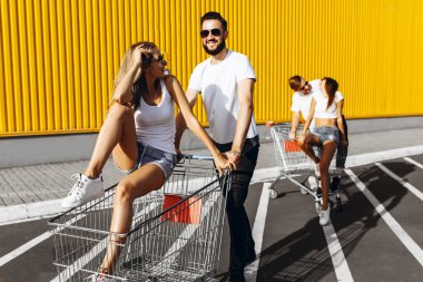 Beyaz t-shirt genç bir grup, mağaza, süpermarket yakınındaki arabaları eğlenceli binmek, arkadaşlar Güneşli havalarda açık havada eğlenin