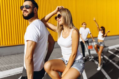 Alışveriş arabalarında eğlenen bir grup mutlu genç, alışveriş arabasına biniyor. güneş ışığı ile yaz günü.