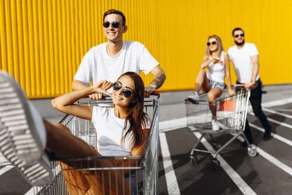 Un gruppo di giovani felici, divertirsi sui carrelli della spesa, liberarsi — Foto Stock