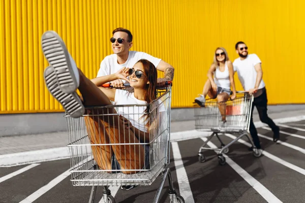 Un gruppo di giovani felici, divertirsi sui carrelli della spesa, liberarsi — Foto Stock