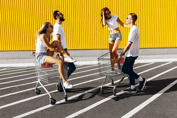 Un groupe de jeunes gens heureux, s'amuser sur des chariots d'achat, débarrasser — Photo