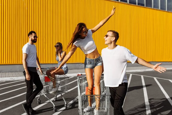 Un gruppo di giovani felici, divertirsi sui carrelli della spesa, liberarsi — Foto Stock