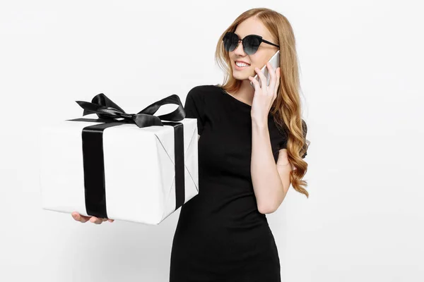 Fiatal lány egy fekete ruhát, és napszemüveg, beszél a telefonon — Stock Fotó