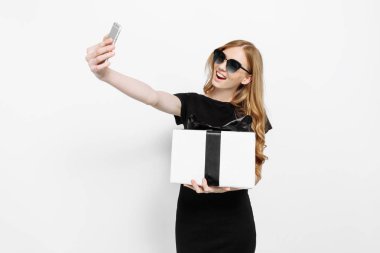 Siyah elbiseli mutlu zarif genç kız, bir hediye tutarak