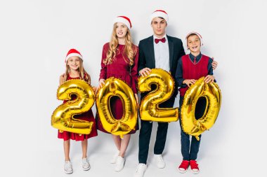 Çocuklu mutlu bir aile Noel Baba şapkası takıyor ellerinde balonlar