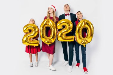 Çocuklu mutlu bir aile Noel Baba şapkası takıyor ellerinde balonlar