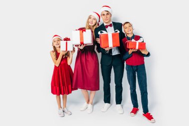 happy Christmas family with kids, in Santa hats, holding Christm clipart