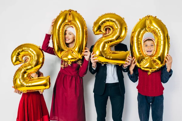 Çocuklu mutlu bir aile Noel Baba şapkası takıyor ellerinde balonlar