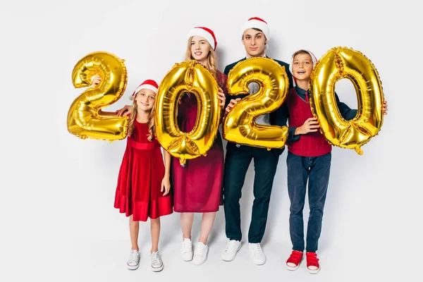 Çocuklu mutlu bir aile Noel Baba şapkası takıyor ellerinde balonlar