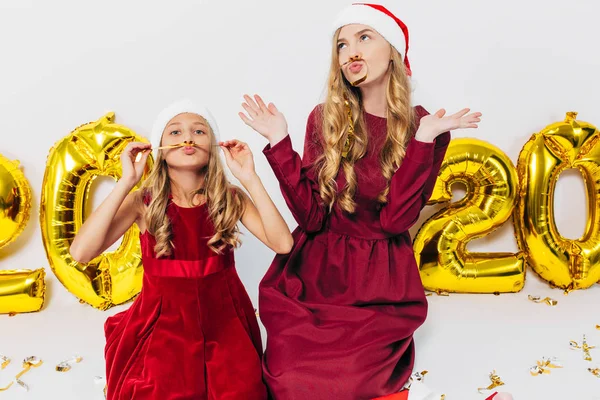 Glada mamma och hennes söta dotter i tomte hattar. En förälder och en — Stockfoto