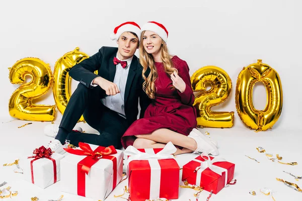 Jovem família, cara e menina em chapéus de Papai Noel, se divertindo com presentes de Natal sentado no fundo branco — Fotografia de Stock