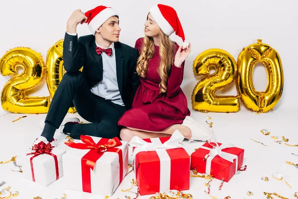 Ung familj, kille och flicka i Santa hattar, ha kul med julklappar sitter på vit bakgrund — Stockfoto