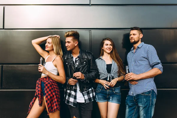 Un grupo de jóvenes y elegantes amigos, chicas y chicos posando juntos contra una pared negra en la ciudad —  Fotos de Stock