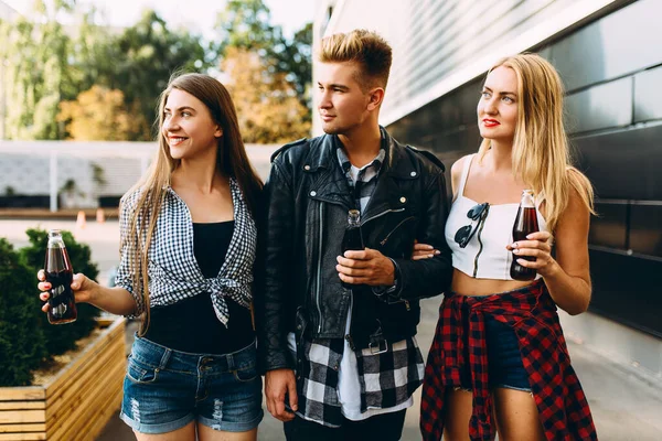 Группа стильных друзей, девушки и парни гуляют вместе по городу, веселятся и пьют напитки — стоковое фото