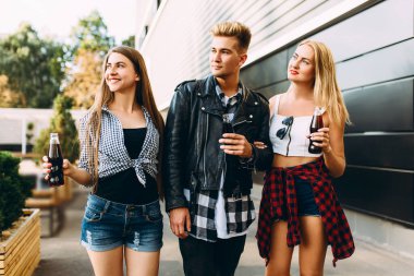 Bir grup şık arkadaş, kızlar ve erkekler şehirde birlikte yürüyor, eğleniyor ve içki içiyorlar.