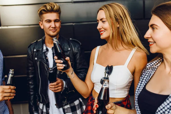 Um grupo de amigos, meninas e caras caminham pela cidade juntos na parede preta, se divertindo e bebendo bebidas. — Fotografia de Stock