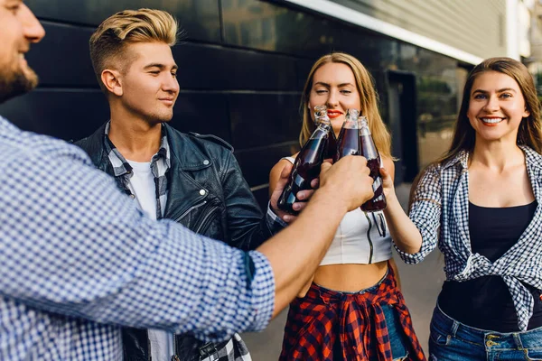 Un grupo de amigos, niñas y chicos caminan por la ciudad juntos en la pared negra, divirtiéndose y bebiendo bebidas. —  Fotos de Stock