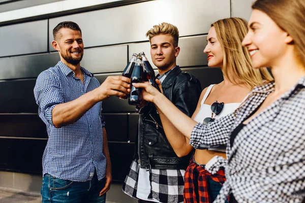 Группа друзей, девушек и парней гуляют по городу вместе у черной стены, веселятся и пьют напитки — стоковое фото