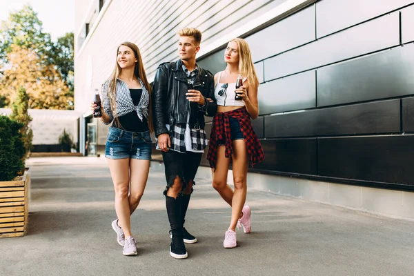 Un gruppo di amici, ragazze e ragazzi alla moda camminano insieme in città, si divertono e bevono bevande — Foto Stock