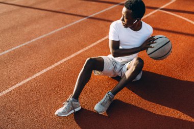 Sportif Afrikalı Amerikalı sahada basketbol oyuncusuyla antreman yaptıktan sonra dinleniyor.