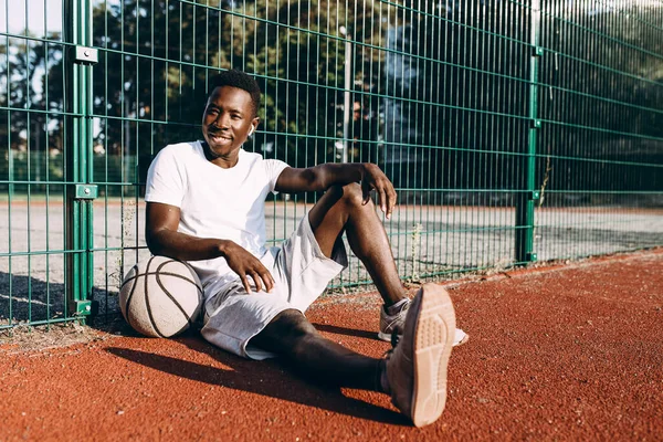 A strong African-American rests after a workout, listening to music in headphones