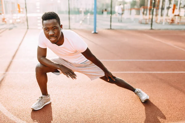 Athlétisme afro-américain faire des exercices d'étirement, se préparer pour l'entraînement matinal au stade — Photo