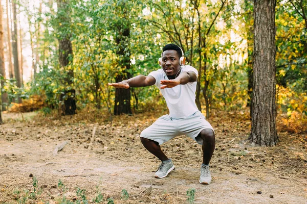 Homme afro-américain athlétique faisant des exercices d'étirement, se préparant pour l'entraînement matinal dans le parc — Photo