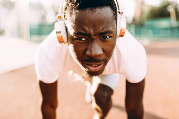 Un jeune athlète afro-américain se tient au début du tapis roulant au stade — Photo