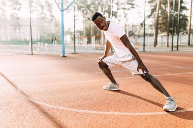Afro-Amerikan atletizmi germe egzersizleri yapıyor, stadyumda sabah antrenmanına hazırlanıyor.