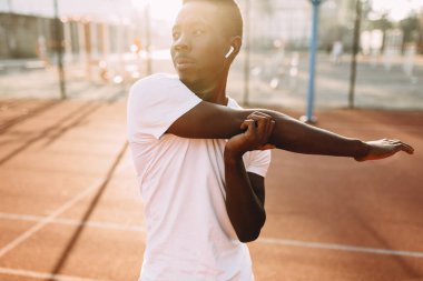 Afro-Amerikan atletizmi germe egzersizleri yapıyor, stadyumda sabah antrenmanına hazırlanıyor.