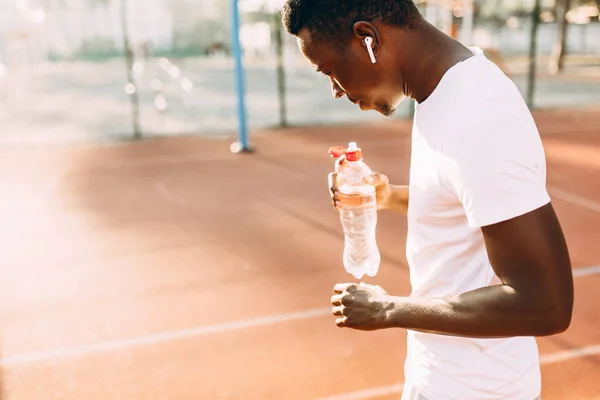 Jeune athlète afro-américain, dans un stade de sport, tenant une bouteille d'eau — Photo