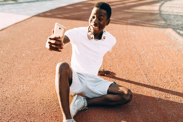 Afro-Américain repose après une séance d'entraînement matinale prend un selfie sur un smartphone — Photo