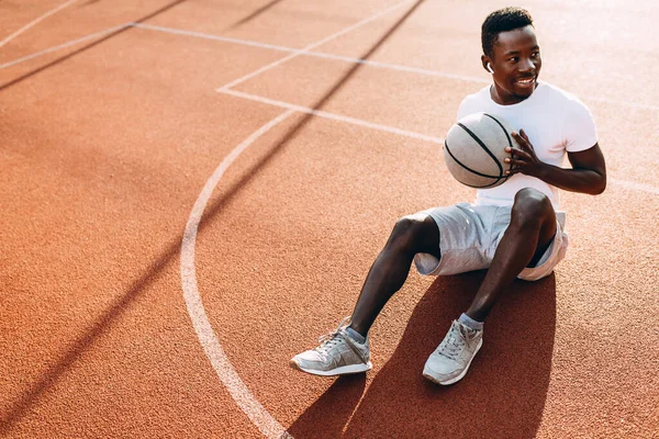 운동 선수인 아프리카 계 미국인 이 농구 선수와 함께 법정에 앉아 운동을 한 후 휴식을 취한다 — 스톡 사진