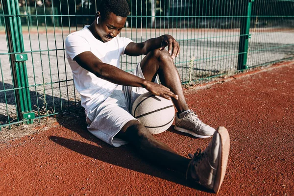 A strong African-American rests after a workout, listening to music in headphones