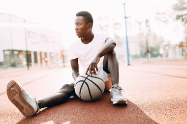 Sportif Afrikalı Amerikalı sahada basketbol oyuncusuyla antreman yaptıktan sonra dinleniyor.