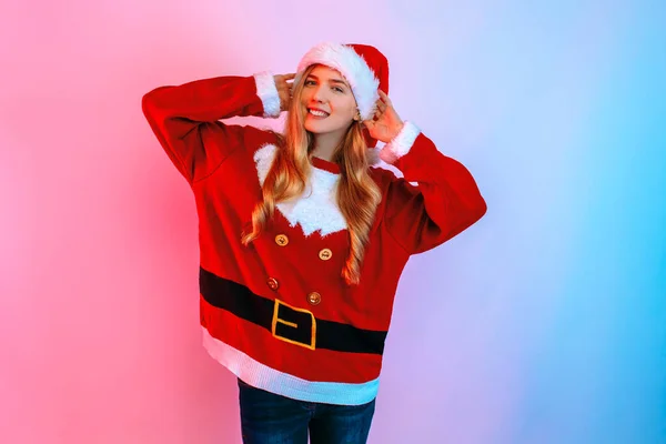 Dívka ve vánočním svetru a Santa klobouk, šťastná dívka pózuje v červené a modré neonové světlo — Stock fotografie