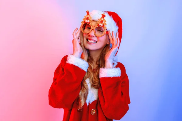 Feliz jovem mulher vestindo Papai Noel chapéu de pé no fundo — Fotografia de Stock