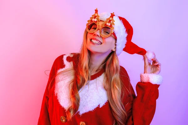 Feliz jovem mulher vestindo Papai Noel chapéu de pé no fundo — Fotografia de Stock