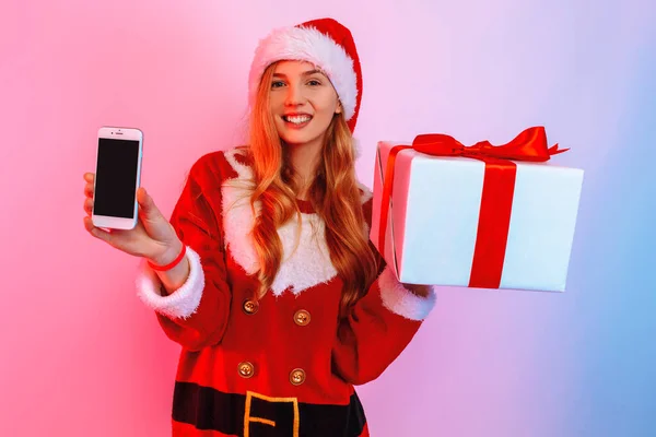 Щаслива молода жінка з різдвяними подарунками показує чистий екран мобільного зв'язку. — стокове фото