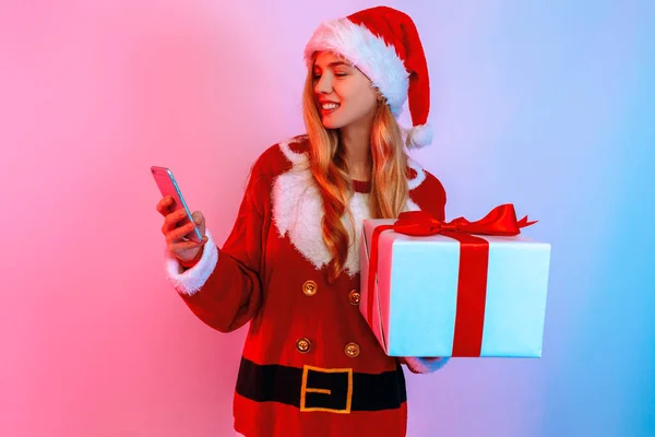 Щаслива молода жінка з різдвяними подарунками використовує смартфон. — стокове фото