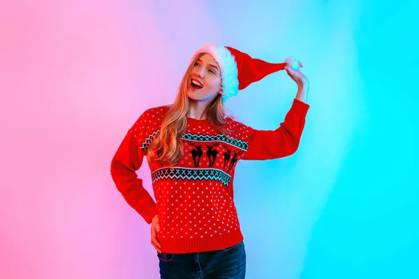 Feliz animado jovem mulher no chapéu de Santa se divertindo e dançando no fundo com luz de néon — Fotografia de Stock