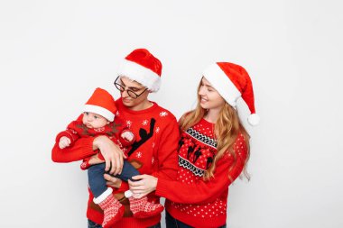 Noel Baba şapkalı mutlu aile, anne ve küçük bebek Noel 'i kutluyor.