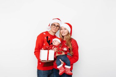 Mutlu aile, anne, baba ve Noel hediyeli küçük bebek