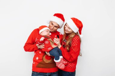 Noel Baba şapkalı mutlu aile, anne ve küçük bebek Noel 'i kutluyor.