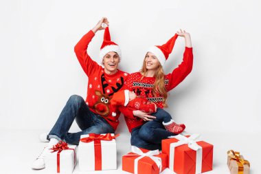 Noel Baba şapkalı mutlu bir aile oturmuş Noel 'i hediyelerle kutluyor.