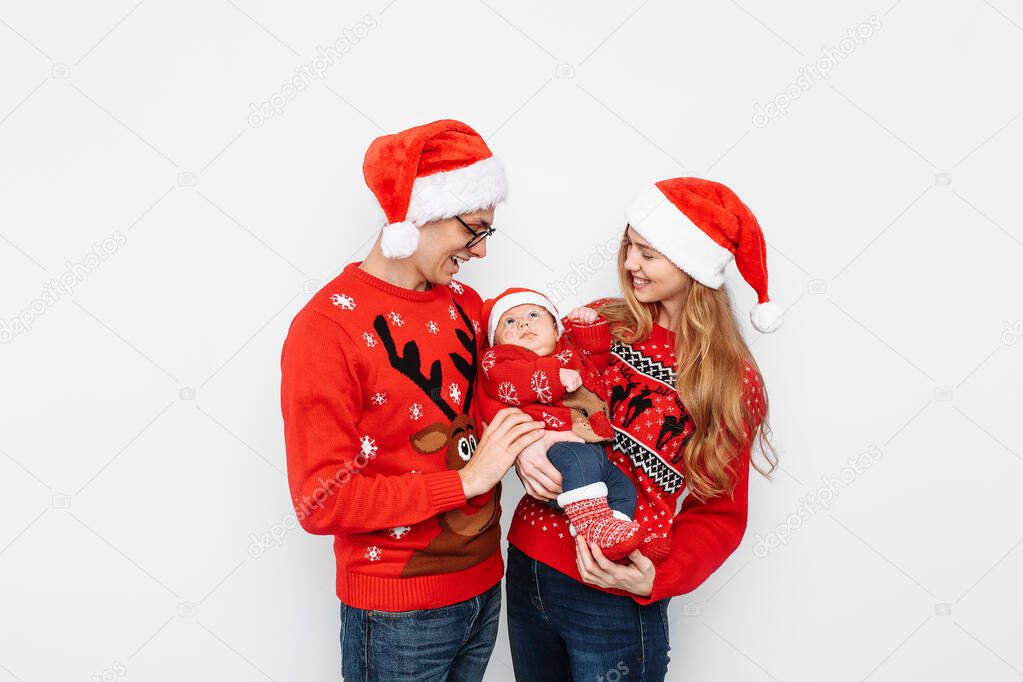 Happy family in Santa hats, mom dad and little baby celebrate Christmas