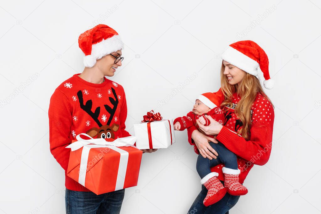 Happy family, dad mom and little baby, celebrate Christmas and give Christmas presents, on a white background