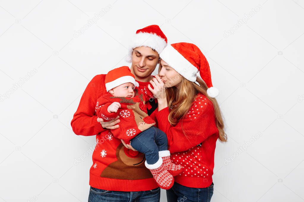 Happy family in Santa hats, mom dad and little baby celebrate Ch