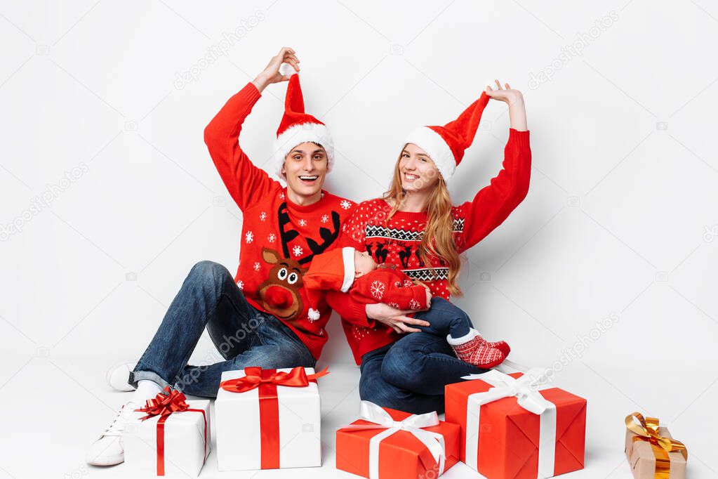 Happy family in Santa hats having fun and celebrating Christmas with gifts while sitting