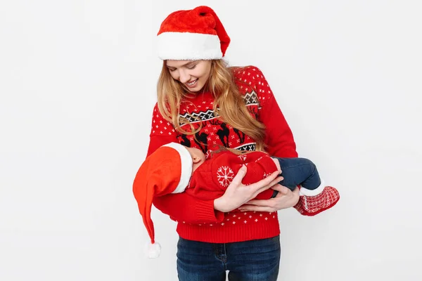 Junge Mutter mit Weihnachtsmütze und kleinem Baby im Weihnachtsmannkostüm auf weißem Hintergrund — Stockfoto